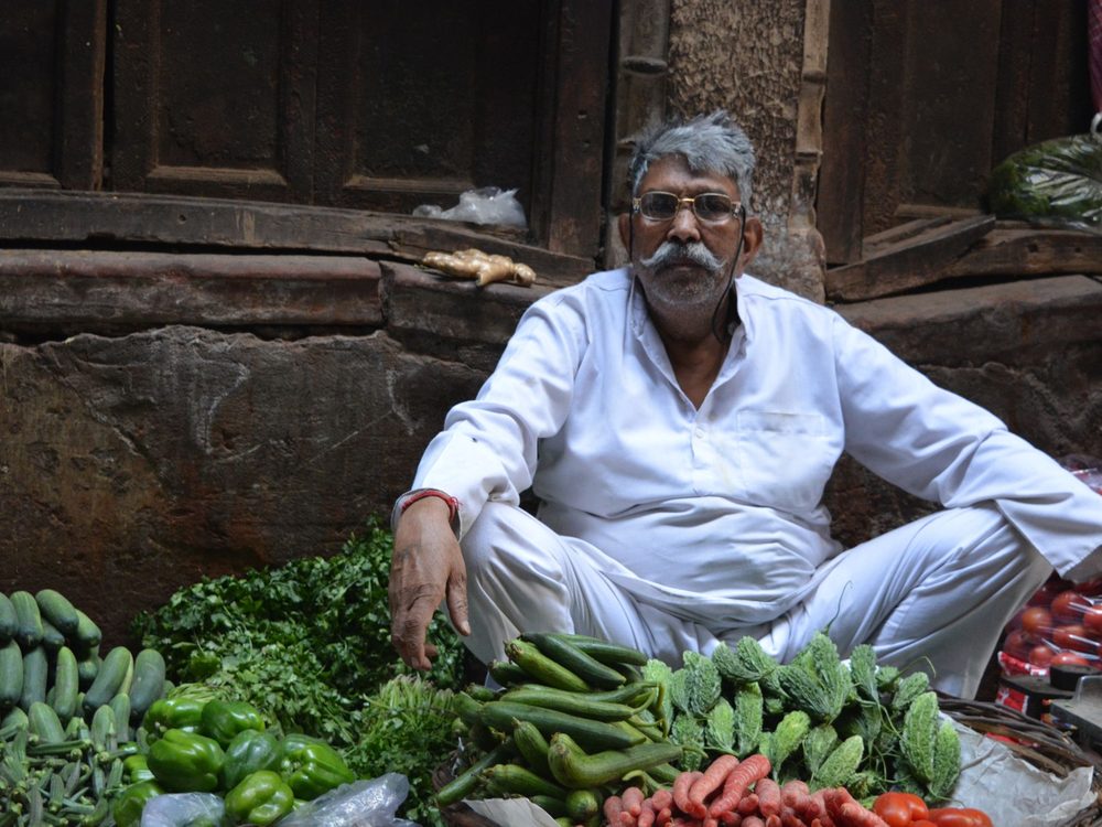 A vegetable seller with the day’s produce laid out at a Delhi market