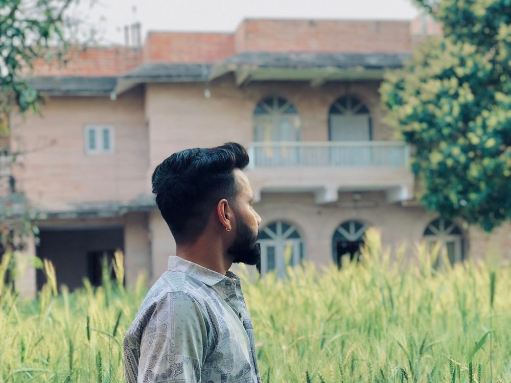 A young farmer standing in his wheat field, reading a message on his phone