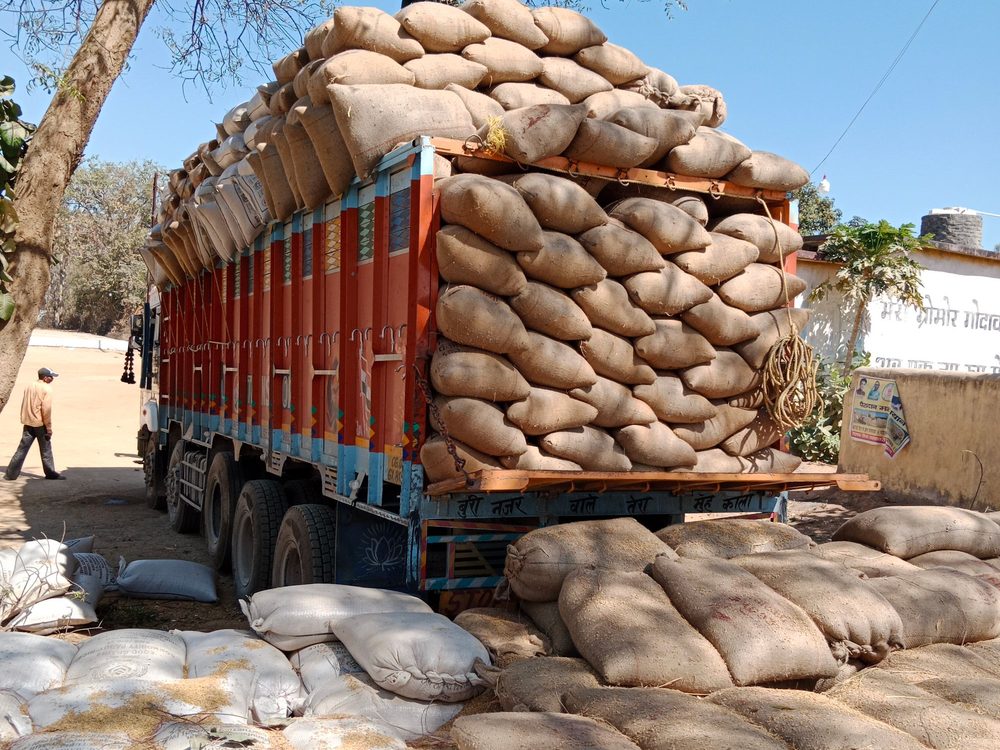 A truck stacked with sacks of produce being loaded in rural Chhattisgarh